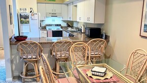 Cocina compacta con alacenas blancas, refrigerador, estufa y microondas.