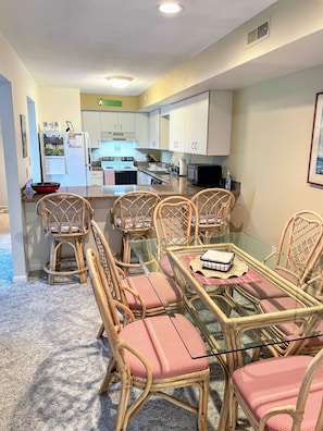 A compact kitchen with white cabinets, a refrigerator, stove, and microwave.