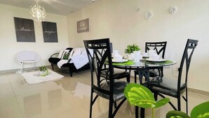 Un espace de salle à manger moderne avec une table ronde, des chaises noires et un lustre.