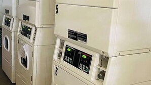 Une rangée de machines à laver à chargement frontal, empilées les unes sur les autres, dans un espace commercial.