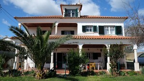 Una casa de dos pisos con balcón, patio cubierto y jardín.