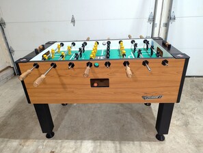 Una mesa de futbolín con base de madera y patas negras.