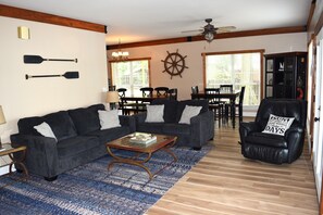 A living room with a sofa, coffee table, and a dining area with chairs and a table.