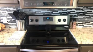 A stainless steel Whirlpool oven with a digital clock, a microwave above it, and a granite countertop.