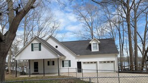 A two-story house with a covered porch, a garage, and a fenced yard.