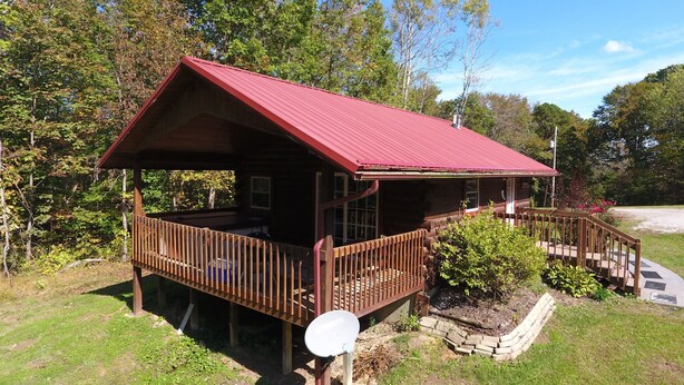 Une cabane en bois avec un toit rouge, une véranda et une antenne parabolique.