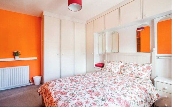 A bedroom with a bed, a dresser, a mirror, and a radiator.