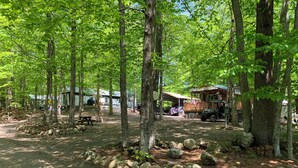 A campground with RVs, a picnic table, and a covered area with an American flag. - Assoc beach, Lakes, Naples Causeway, restaurants, shops, boat- jet ski rentals. (Naples)