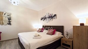 Ein ordentlich eingerichtetes Schlafzimmer mit einem Bett, Nachttischen und einem an der Wand befestigten Kunstwerk.