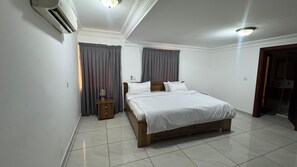 A bedroom with a bed, a nightstand, and a door.