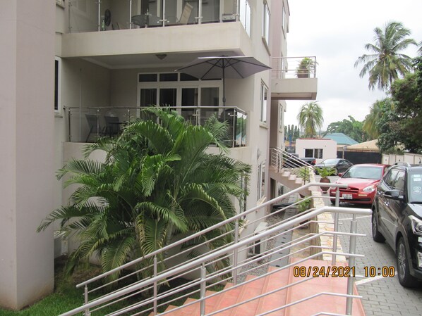 A multi-story building with a balcony, a staircase, and parked cars. - 160 sqm 2 Bedroom Apartment Bertha's Court  (Accra)