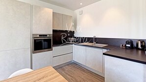 A modern kitchen with a built-in oven, a sink, and a countertop with a kettle and a coffee maker. - Viva Riviera Rue Hoche Luxury Collection (Cannes)