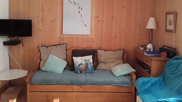 A wooden-paneled room with a bed, a TV, a lamp, and a picture on the wall. - Beautiful ground-floor apartment rated 3 keys by Clévacances. Private, enclosed garden. (Mont-Dore)