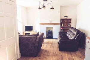 A living room with a fireplace, a television, a bookshelf, and a leather sofa.
