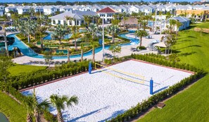 Et resort med et stort sandstrand, flere swimmingpools og en række villaer i baggrunden.