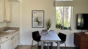 A modern kitchen with a dining area, wooden ceiling, large windows, and a framed artwork on the wall. - Condo with amazing views and 3 pools (Indian Wells)