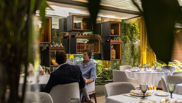 A restaurant with tables set for dining, surrounded by shelves with books and decorative items. - Casa Hedera (Mexico City)