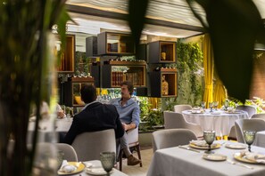 A restaurant with tables set for dining, surrounded by shelves with books and decorative items. - Casa Hedera (Mexico City)
