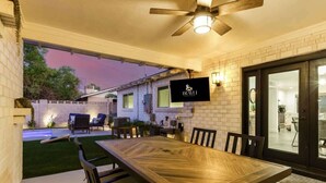 Une terrasse couverte avec une table et des chaises, un ventilateur de plafond et une enseigne indiquant «IRAVI».