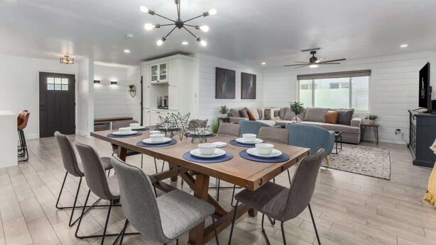 Un espace repas moderne avec une table en bois dressée pour six personnes, entourée de chaises à revêtement gris.