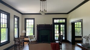 A spacious room with hardwood floors, a fireplace, a large window, and a chandelier. - Spacious Home and Private Getaway (Fayette)