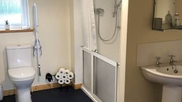 A bathroom with a toilet, shower, and sink.