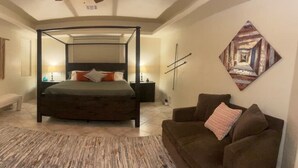 A bedroom with a four-poster bed, a TV, a bench, and a couch.