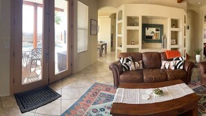 A spacious living room with a brown leather sofa, a wooden coffee table, and a patterned rug.
