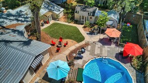 Un cortile residenziale con piscina, mobili da patio e una zona relax coperta.