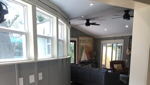Un corridoio con pavimento in legno, parete grigia con una finestra e una ventola a soffitto.