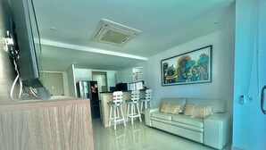 A modern living room with a white sofa, a coffee table, and a painting on the wall. - Apartamento Vista al Mar (Cartagena)