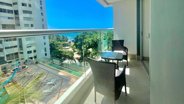 A balcony with a glass railing, a table, and two chairs. - Apartamento Vista al Mar (Cartagena)