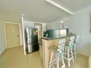 A modern kitchen with a stainless steel refrigerator, a wooden island with bar stools, and a door leading to another room. - Apartamento Vista al Mar (Cartagena)