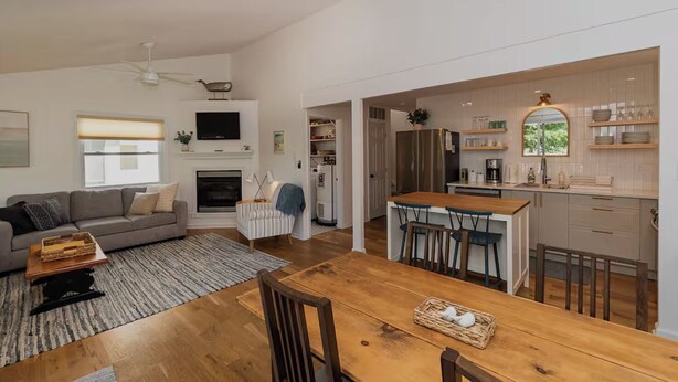 Amplia sala de estar con chimenea, comedor con mesa de madera y cocina con barra.