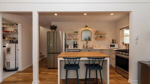 Una cocina moderna con una isla central, electrodomésticos de acero inoxidable y vista al área de estar contigua.