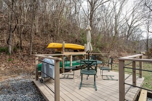 Une terrasse en bois avec une table et des chaises, un kayak et un espace abrité.