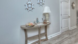 Un pasillo con una consola de madera, una puerta blanca y decoración náutica.
