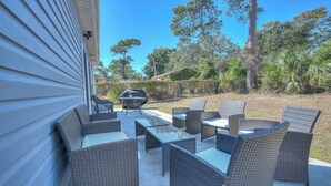 Un patio al aire libre con mobiliario de mimbre y una parrilla.