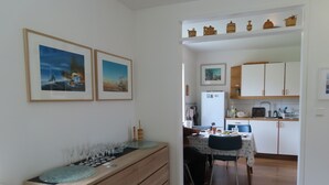 Un coin repas avec un buffet en bois, une cuisine à l’arrière-plan et des tableaux encadrés au mur.
