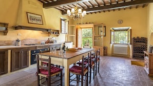 Una cocina rústica con una mesa de madera, sillas y una estantería para vinos.