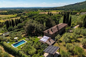 A villa with a swimming pool, solar panels, and a garden.