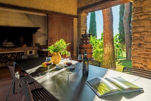 A dining table with wine glasses, a bottle, and a menu. There is a stone wall and a view of trees.