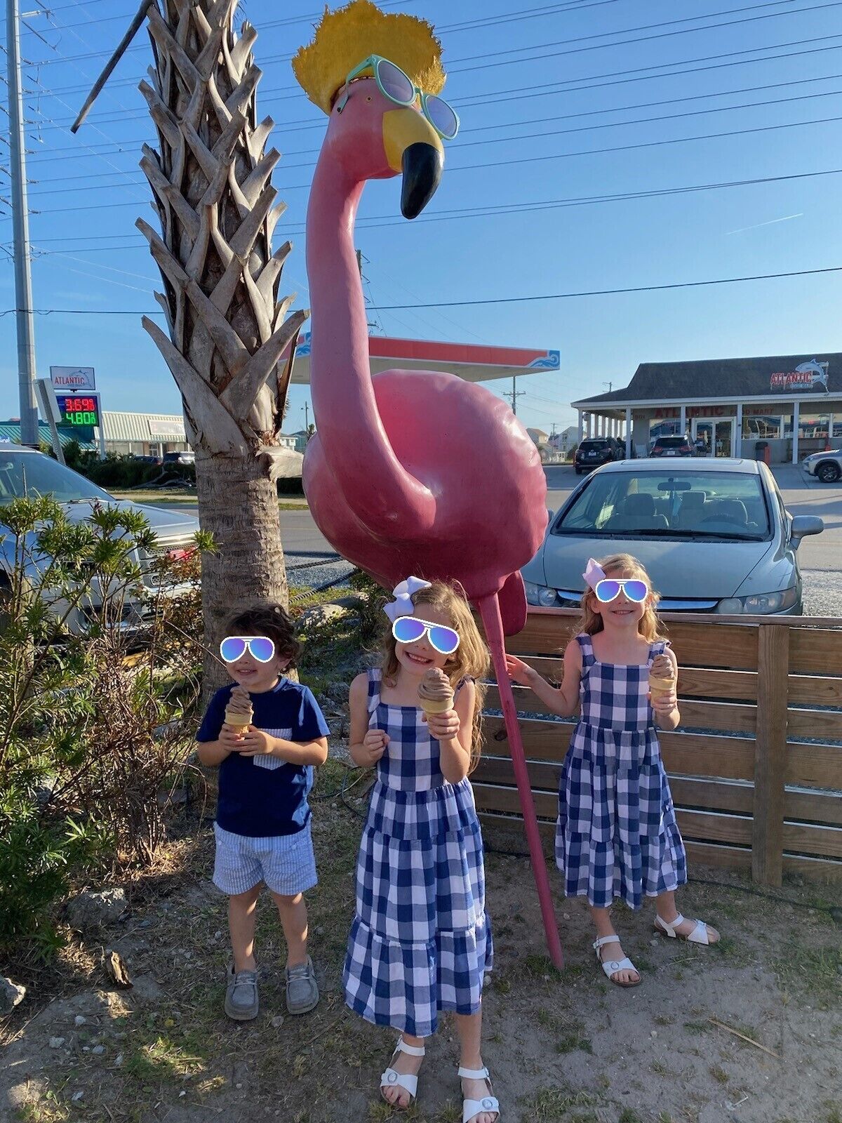 Eine große, rosa Flamingo-Statue, eine Palme und im Hintergrund eine Tankstelle.
