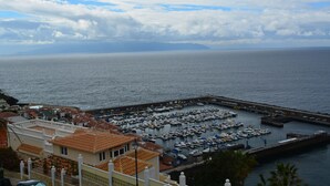 A marina with boats docked, a pier, and buildings with red-tiled roofs.