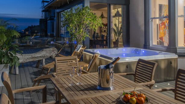 Une terrasse en bois avec des sièges d’extérieur et un jacuzzi.