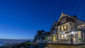 Une grande maison à plusieurs étages, dotée d’un balcon offrant une vue sur la côte.