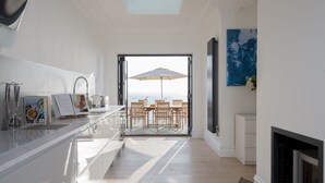Une cuisine moderne avec vue sur la mer, un coin repas avec des sièges à l’extérieur et une cheminée.