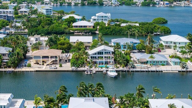 Zona residencial costera con casas, un puerto deportivo y una piscina.
