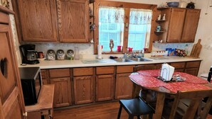 Una cucina con mobili in legno, un piano di lavoro, un lavandino e un'area pranzo con tavolo e sedie.