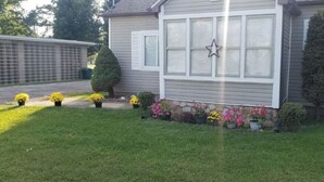 Una casa con un prato curato, una stella decorativa alla finestra e una varietà di fiori colorati nel giardino.